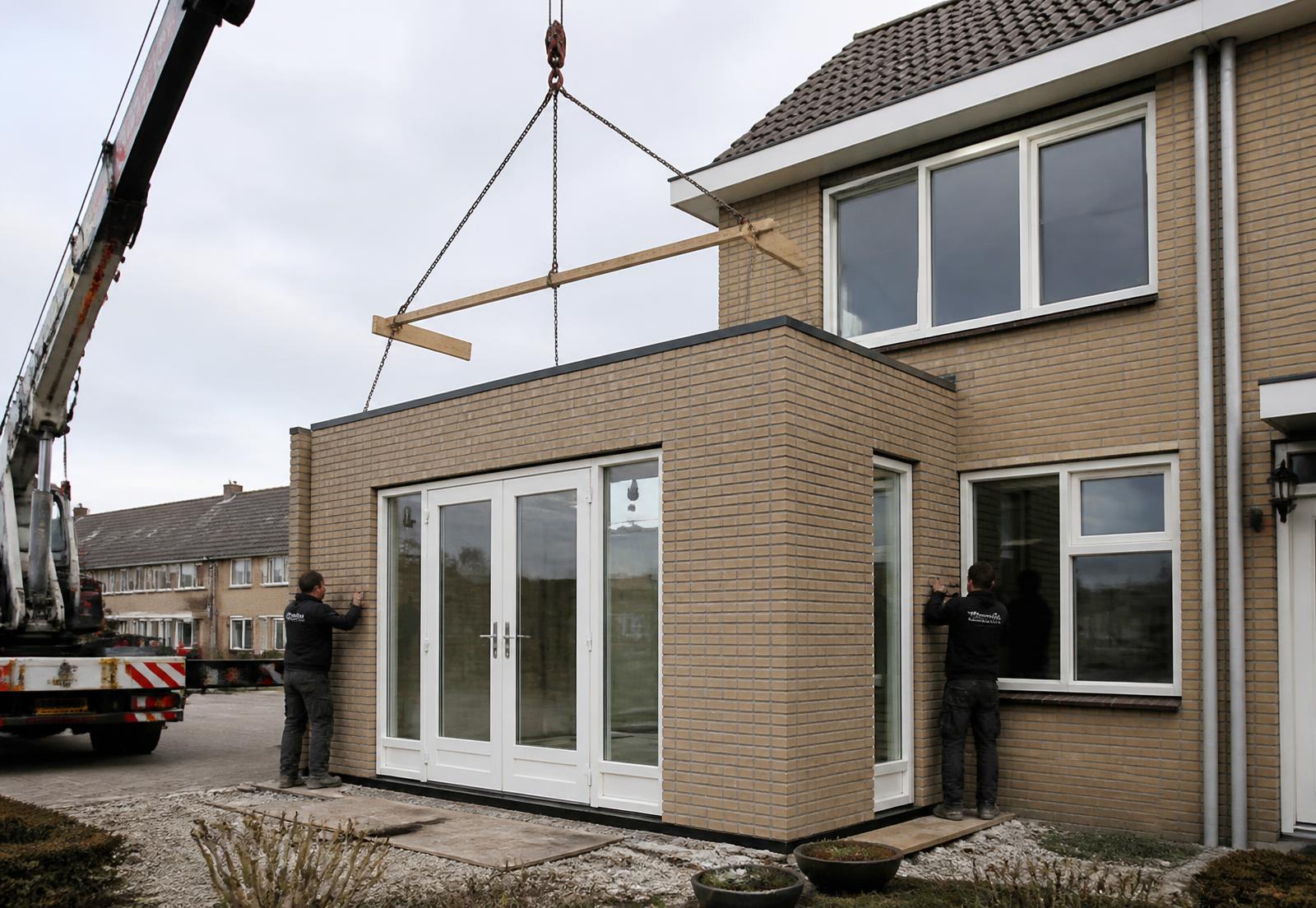 Prefab aanbouw wordt geplaatst met een kraan
